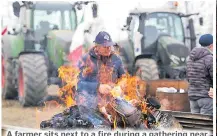  ?? Picture: AP Photo/Luca Bruno ?? A farmer sits next to a fire during a gathering near the highway junction in Melegnano, near Milan,
Italy, Wednesday.