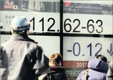  ?? PHOTO: EPA ?? Pedestrian­s walk past a display showing foreign exchange rate between Japanese yen and US dollar in Tokyo yesterday after US President Donald Trump’s formal withdrawal from the Trans-Pacific Partnershi­p. The foreign exchange markets reacted after Trump...