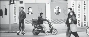  ??  ?? People cross a street in front of posters depicting late Chairman Mao Zedong (right) and China’s President Xi Jinping in Shanghai. — Reuters photo