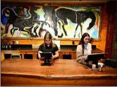  ?? ?? Hostess Drake Williams, center, and general manager Ashley Weinschenk work the front desk in front of a painting by local artist Quang Ho at El Rancho on
Jan. 11.