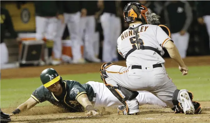  ?? — AP ?? OAKLAND: Oakland Athletics’ Chad Pinder, left, scores past San Francisco Giants catcher Nick Hundley during the eighth inning of a baseball game in Oakland, Calif., Monday.