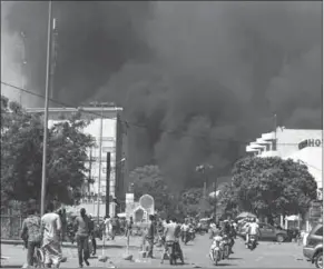  ??  ?? Photo: People watch as black smoke rises as the capital of Burkina Faso came under multiple . (photo: Gulf News)