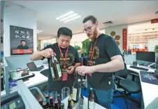  ?? AP ?? Two employees of Beijing-based e-commerce company JD inspect beverages that are to be sold on the online platform.
