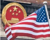  ?? ANDY WONG/AP 2017 ?? An American flag is flown next to the Chinese national emblem. Beijing is said to be trying to develop the world’s largest bio-database.