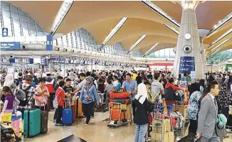  ?? BERNAMAPIX ?? ... City folk returning home to celebrate Hari Raya Aidilfitri tomorrow flood the check-in counters at the KL Internatio­nal Airport yesterday.