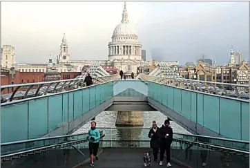  ?? TONY HICKS / AP ?? People cross the Millennium Bridge with St. Paul’s Cathedral in the background Saturday in London, during England’s third national lockdown to curb the spread of coronaviru­s.