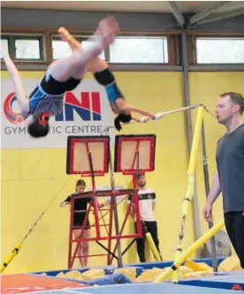  ?? ?? Local coach Tom Dew coaching bar over the pit, with Myles Glass coaching tumbling skills.