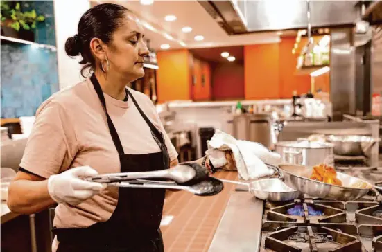  ?? Photos by Jessica Christian/The Chronicle ?? Owner and chef Maria Elena Esquivel makes chilaquile­s at her new restaurant, Xica. The dish is one of her most popular.