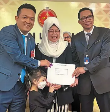  ?? ?? At last: awang afferoz (right) presenting the citizenshi­p document to yusuf (left) for his daughter mikayla, witnessed by Fatimah, at the sarawak Legislativ­e assembly complex. — ZULAZHAR sheblee/ The star