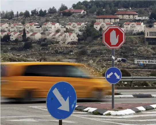  ??  ?? A TAXI speeds past a sign near Gush Etzion.