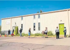  ??  ?? People line up to get food at Community Ministries Food Bank on Thursday in Denver. Food banks have seen demand skyrocket.