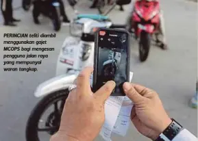  ??  ?? PERINCIAN teliti diambil menggunaka­n gajet MCOPS bagi mengesan pengguna jalan raya yang mempunyai waran tangkap.