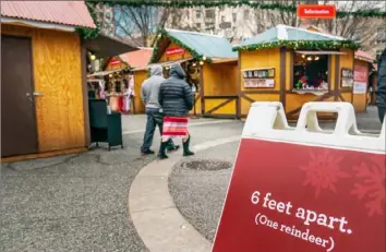  ?? Andrew Rush/Post-Gazette photos ?? People walk past a reminder of social distancing at the Peoples Gas Holiday Market.