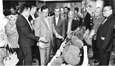  ??  ?? Abang Johari being briefed by Dr Tan (second left) on the various species of durian on display at an exhibition held in conjunctio­n with the MoU signing ceremony. — Photo by Tan Song Wei