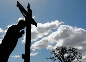  ??  ?? Ein Gläubiger im Kloster von Penteli bei Athen berührt mit seiner Stirn ein Kreuz während der traditione­llen Nachstellu­ng der Abnahme von Jesus am Karfreitag.