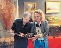  ??  ?? LEFT: Dealer Jeff Hengesbaug­h shows Emmanuel Ameloot an antique military piece.