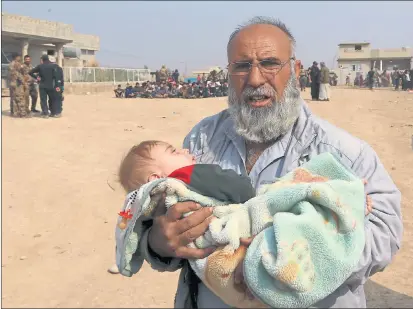  ??  ?? VICTIMS OF THE BATTLE: A man holds a child as civilians leave their houses in the village of Tob Zawa, near Mosul. Picture: Khalid Mohammed/AP