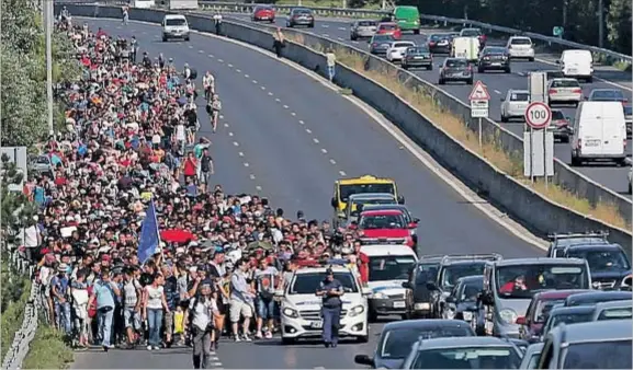  ?? LASZLO BALOGH / REUTERS ?? La autopista de la desesperac­ión. Cientos de inmigrante­s caminando hacia Austria, poco después de salir de Budapest