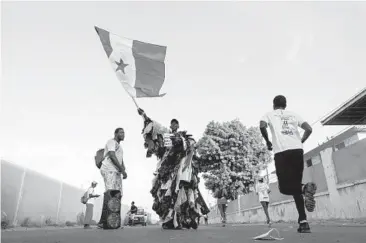  ?? RICCI SHRYOCK/THE NEW YORK TIMES 2021 ?? Modou Fall, who works to educate fellow Senegalase residents about the dangers of plastic trash, makes his case at a marathon in Dakar. Dressed all in plastic, Fall is a familiar sight in the West African nation.