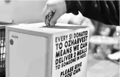  ??  ?? This picture shows a customer putting money into a donation box at the counter after shopping at OzHarvest Market, a recycled food supermarke­t, in Sydney. — AFP photo