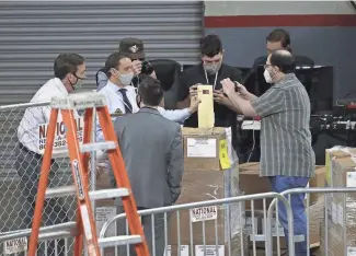  ?? PATRICK BREEN/THE REPUBLIC ?? Former Arizona Secretary of State Ken Bennett, far left, takes custody of a pallet of ballots Thursday before an audit of 2.1 million election ballots at Veterans Memorial Coliseum.