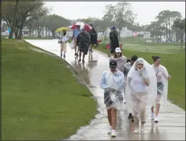  ?? MARTA LAVANDIER — THE ASSOCIATED PRESS ?? Spectators exit the course as heavy rain delays the final round of the Cognizant Classic on Sunday in Palm Beach Gardens, Fla.