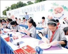  ?? PROVIDED TO CHINA DAILY ?? Schoolchil­dren and local residents gather at the lakeside to savor the first batch of hairy crabs coming from Yangcheng Lake on Sept 23.