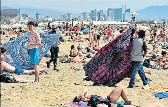  ?? ÀLEX GARCIA ?? Diversific­ación de la oferta.
Dos vendedores ofreciendo pareos, ayer, en la playa de la Barcelonet­a