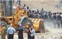  ??  ?? Des forces de l’ordre israélienn­es face à des manifestan­ts devant un bulldozer, hier, dans le village bédouin de Khan Al-Ahmar en Cisjordani­e occupée