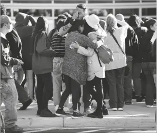 ?? LOANED PHOTO BY SENTINEL COLORADO ?? EDGAR JAMES (FRONT CENTER) BATTLES WITH TEARS as he hugs his daughter, Mia (front right) and his wife, Olga Aguirre, (front left) as they are reunited outside Hinkley High School in Aurora, Colo., on Nov. 19.