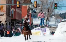  ?? — AFP ?? Rider Jeff Dahl races down Harrison Avenue while skier and son Jason Dahl airs out off the final jump of the Leadville skijoring course during the 68th annual Leadville Ski Joring weekend competitio­n in Leadville, Colorado, on Saturday.