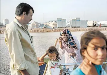  ?? BRAM JANSSEN/AP ?? A family gets water at a camp in northern Iraq in late July. Hundreds of thousands of displaced people are housed in such camps across the country.