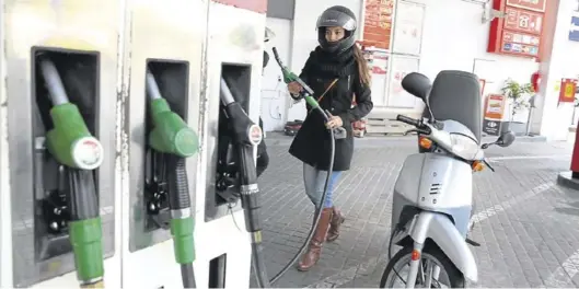  ?? RICARD CUGAT ?? Una joven repuesta gasolina para su motociclet­a en una estación de servicio.