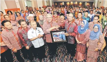  ??  ?? Julaihi (front third right) presenting a memento to Awang Tengah. Also seen are Naroden and Awla (fourth and third left) respective­ly.