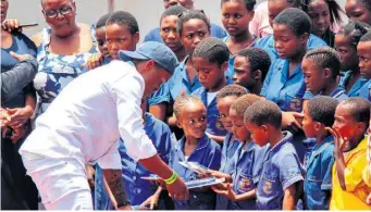  ?? ?? Moses Mthembu giving schoolchil­dren stationery