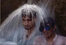  ?? B.K. BANGASH — THE ASSOCIATED PRESS ?? People sit under a stream to cool off as the temperatur­e reaches about 104 degrees on July 1 in the suburbs of Islamabad, Pakistan. Last month was Earth’s hottest June on record.