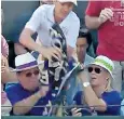  ??  ?? An unidentifi­ed Wimbledon spectator, left, wrestled the towel from a young fan’s grip