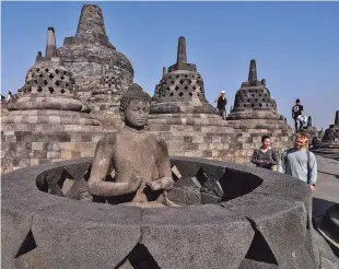 ??  ?? ABOVE: Tourists on Monday inspect a Buddha statue at Borobudur Temple in Magelang, Central Java, Indonesia.