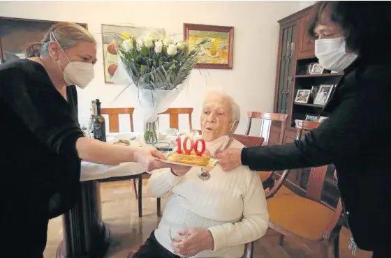  ??  ?? Ángela Eraso, una vez vacunada, sopla las velas por su 100º cumpleaños junto a sus hijas Mari Cruz (izda) y Fabiola Belzunegui (dcha).