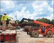  ??  ?? BELOW: Steel is taken off a trailer at the site of the School.