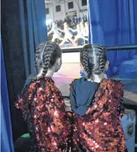  ?? NIKKI SULLIVAN/CAPE BRETON POST ?? Two young dancers from Sydney watch through the curtains backstage waiting for their group hip hop dance. From left, Sophie Swan, 9, and Kerrissa Smith, 9, both dance with D&R Dance Ltd.