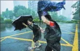  ?? MAO SIQIAN / XINHUA ?? Pedestrian­s struggle to cross a roadway amid heavy rains in Shenzhen, Guangdong province, on Sunday.