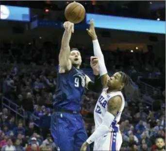  ?? MICHAEL PEREZ - THE ASSOCIATED PRESS ?? Orlando’s Nikola Vucevic, left, takes a jump shot night at Wells Fargo Center. over the Sixers’ Richaun Holmes Saturday