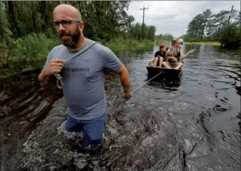  ?? JONATHAN DRAKE / REUTERS ?? A volunteer from the community pulls a boat holding a mother and several of her children during their rescue from rising flood waters in the aftermath of Hurricane Florence, in Leland, North Carolina on Sunday.