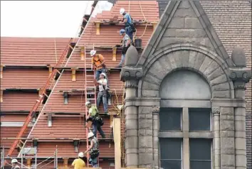  ?? Darrell Sapp/Post-Gazette ?? Workers form a chain as they pass new terra cotta clay tiles to shingle the roof of the Allegheny County Courthouse in May.