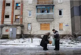  ?? (Thomas Peter/Reuters) ?? A DRIVER delivers groceries to a woman who is one of the few remaining residents in a neighborho­od that was heavily damaged by fighting in the frontline town of Lyman, amid Russia’s attack on Ukraine, December 15, 2023.