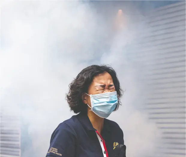  ?? ANTHONY WALLACE / AFP via Getty
Images ?? A woman reacts after riot police fire tear gas to disperse protesters taking part in a pro- democracy rally against a proposed new national security
law in Hong Kong on Sunday. Washington said China’s proposed legislatio­n could lead to U. S. sanctions.