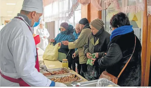  ?? SERGEY KOZLOV / EFE ?? Residentes reciben comida caliente en Jarkov.