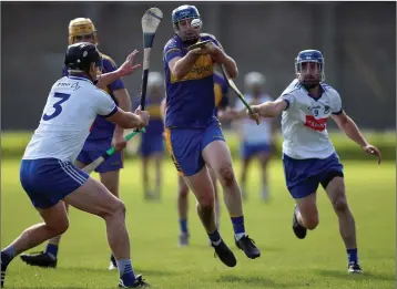  ??  ?? Carnew’s Wayne Kinsella looks to squeeze through past Éire Óg’s Billy Cuddihy and Sean Lawless.