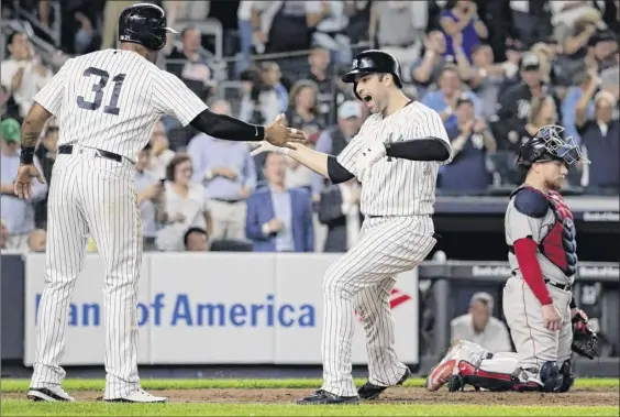  ?? Photos by Julio Cortez / Associated Press ?? The New York Yankees’ Neil Walker, right, celebrates with Aaron Hicks (31) after hitting a three-run home run Tuesday in New York.